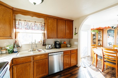 Kitchen with stainless steel dishwasher, brown cabinetry, light countertops, and range with electric stovetop