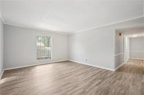 Unfurnished room with crown molding, wood finished floors, and baseboards