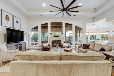 Living room with a tray ceiling, a lit fireplace,