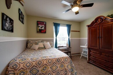 Bedroom with a ceiling fan and dark colored carpet