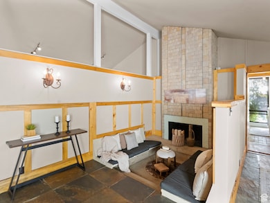 Living area featuring a brick fireplace, stone tile floors, and high vaulted ceiling