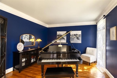 Flexible front room with hardwood floors and large windows. Ideal as a music room, office, or additional living space.