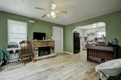 Living room with a brick fireplace, light hardwood