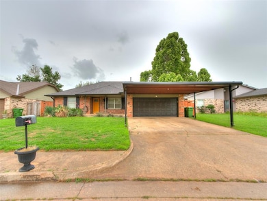 View of front of property with an attached garage, brick siding, concrete driveway, and an attached carport