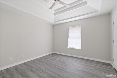 Spare room featuring a tray ceiling, wood finished floors, and ceiling fan