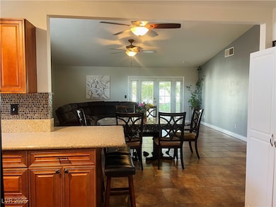 Kitchen with light stone countertops, brown cabinets, backsplash, and vaulted ceiling