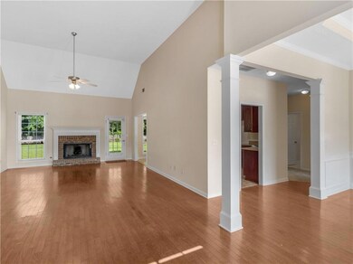 Unfurnished living room featuring ornate columns, ceiling fan, plenty of natural light, wood finished floors, and high vaulted ceiling