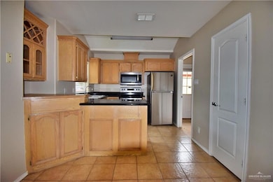 Kitchen with a peninsula, light brown cabinets, visible vents, and stainless steel appliances