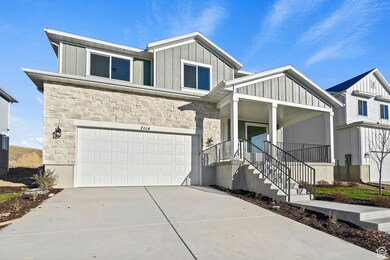 View of front of property featuring board and batten siding, stone siding, driveway, a garage, and a porch
