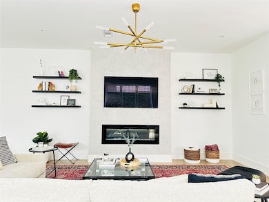 Living area with a large fireplace, wood finished floors, recessed lighting, and a chandelier