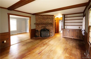 Den with beamed ceiling, brick fireplace, wood sto