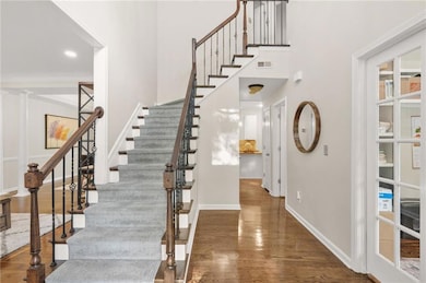 Stairway with wood finished floors, a high ceiling, baseboards, and ornamental molding