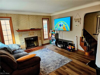 Living room with brick wall, dark hardwood / wood-style floors, and a stone fireplace