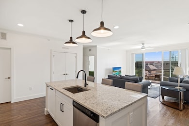 Kitchen with white cabinetry, light stone countertops, stainless steel dishwasher, dark wood finished floors, and recessed lighting