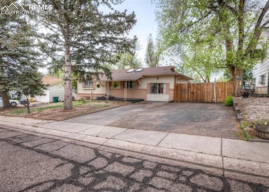 Single story home featuring asphalt driveway, fenc