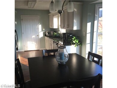 Kitchen. Laundry room door at edge of kitchen. Dining area flooded with natural light.