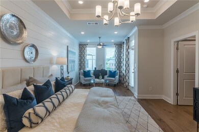 Natural light streams in through large windows, highlighting the rooms high ceilings and neutral tones.  This photo is of the Chamberlain model and does not represent this homesite.