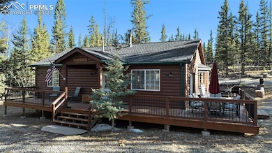 View of front of house with faux log siding, a wooden deck, and a shingled roof