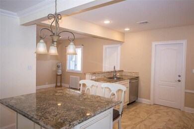 Kitchen featuring radiator heating unit, dishwasher, dark stone counters, decorative light fixtures, and ornamental molding