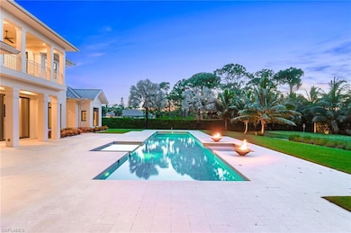 Pool at dusk featuring a patio area and a hot tub