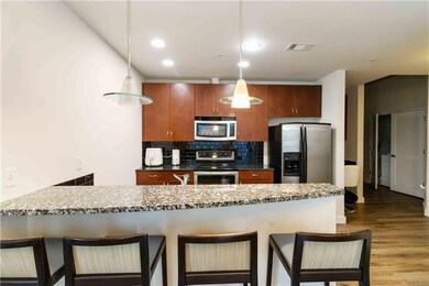 Kitchen with dark stone counters, decorative backsplash, a kitchen breakfast bar, stainless steel appliances, and a peninsula