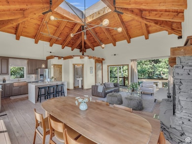 Dining area with beam ceiling, light wood-style flooring, wood ceiling, and high vaulted ceiling