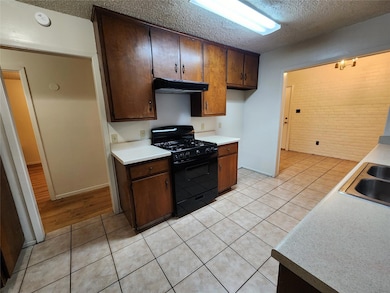 Kitchen with black range with gas stovetop, a tex