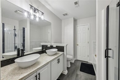 Bathroom with a stall shower, toilet, tile patterned floors, and double vanity