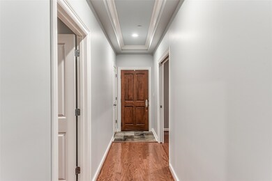 As you enter the unit, you are greeted by a long foyer. The secondary bedroom is to the right, with pocket doors, and the kitchen is accessible through the door to the left.
