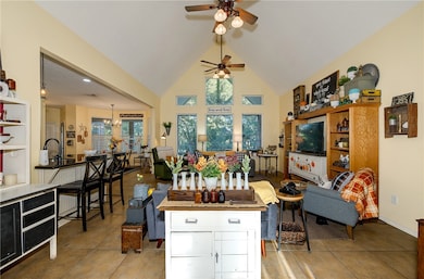 Living room featuring high vaulted ceiling, light tile patterned floors, a ceiling fan, and a chandelier