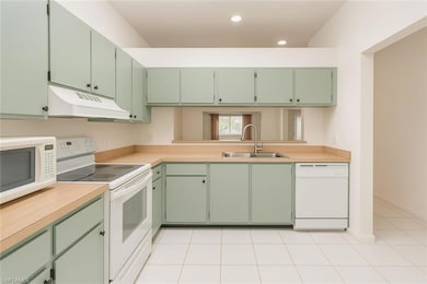 Kitchen featuring green cabinetry, white appliances, light countertops, under cabinet range hood, and recessed lighting