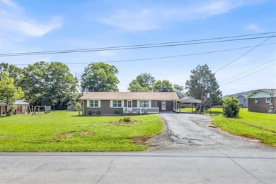 Single story home featuring driveway, a front yard, and a detached carport