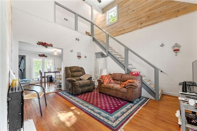Living room with stairs, wood-type flooring, a towering ceiling, and plenty of natural light