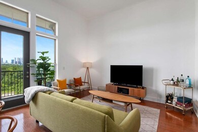 Living room with plenty of natural light, wood finished floors, a towering ceiling, and a view of city
