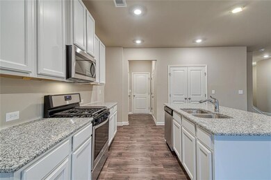 Kitchen featuring stainless steel appliances, dark wood-style floors, recessed lighting, white cabinets, and light stone countertops
