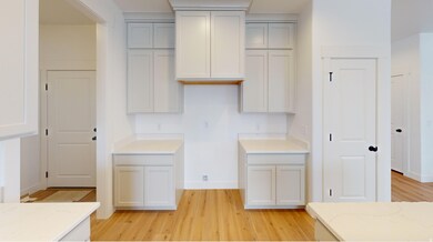 Kitchen with light wood-style floors, white cabinetry, and light stone countertops