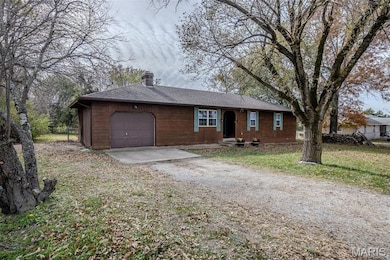 Single story home featuring driveway, a garage, a chimney, a front lawn, and a shingled roof
