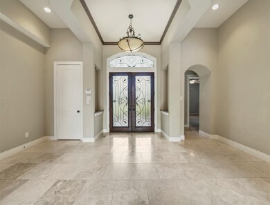 Bright and spacious foyer with lots of natural light. Notice the vaulted ceilings with recessed lighting and travertine tile.