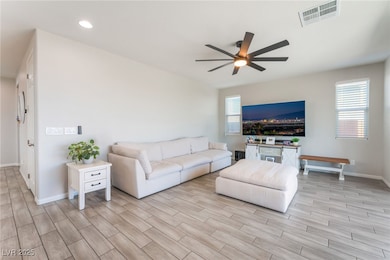 Living area with ceiling fan, light wood-style flo