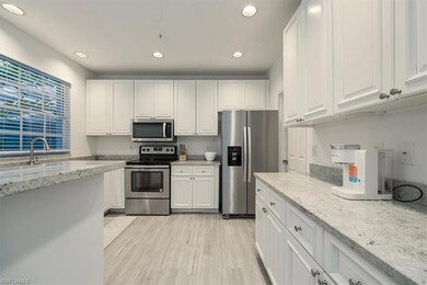Kitchen featuring stainless steel appliances, white cabinetry, recessed lighting, and light stone countertops
