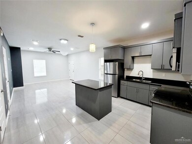 Kitchen featuring a ceiling fan, a sink, freestanding refrigerator, gray cabinets, and a kitchen island