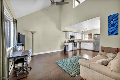 Living room featuring ceiling fan, baseboards, hig