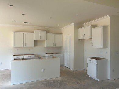 Kitchen with a kitchen island, ornamental molding, unfinished concrete flooring, and white cabinets