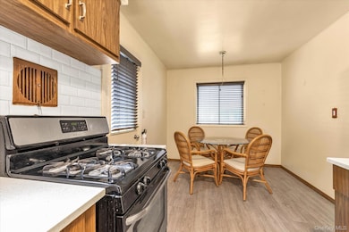 Kitchen with stainless steel gas range oven, brown cabinets, light wood-style floors, crown molding, and decorative backsplash