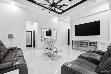 Living area featuring ceiling fan, coffered ceiling, light marble finish flooring, a towering ceiling, and beamed ceiling