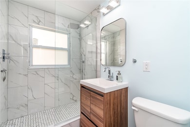 Bathroom featuring vanity and a marble and tile sh