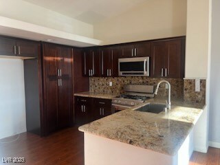 Kitchen with stainless steel appliances, a peninsula, dark wood-style flooring, and tasteful backsplash