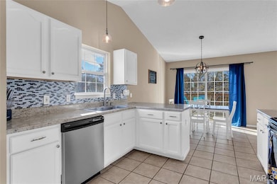 White cabinets stainless appliances and trendy back splash and vaulted ceiling