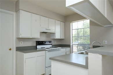 Kitchen featuring white electric stove, white cabi