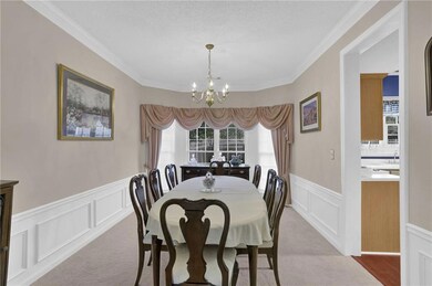 Carpeted dining space with wainscoting, a chandeli